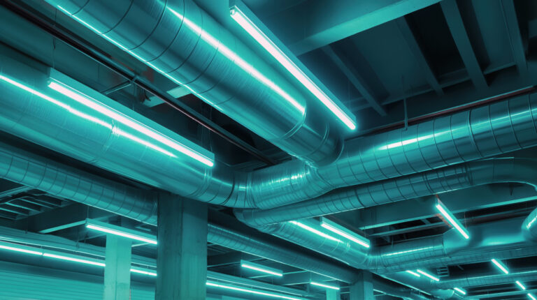 Modern hvac ductwork system illuminated by blue neon lights, showcasing industrial design and clean installation in a building ceiling.